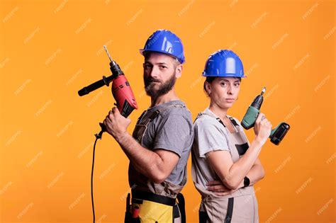 premium photo confident renovators standing with electric power drills looking at camera and