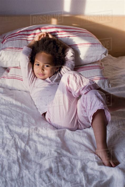 Little girl lying on bed in pajamas - Stock Photo - Dissolve