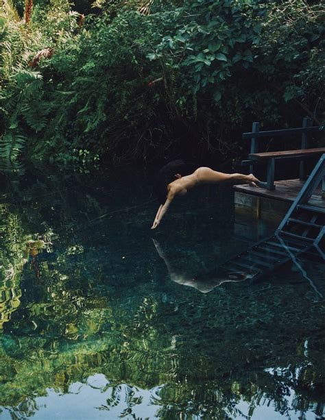 A Naked Woman Floating In Water Next To A Wooden Dock With Stairs