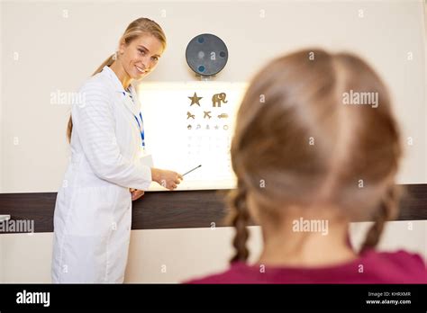 Portrait Of Pretty Female Ophthalmologist Pointing At Eye Chart Testing