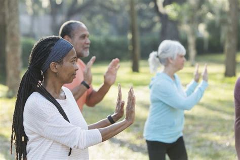 Group Of Older People Doing Yoga In The Park With Their Hands Together And Looking At Something