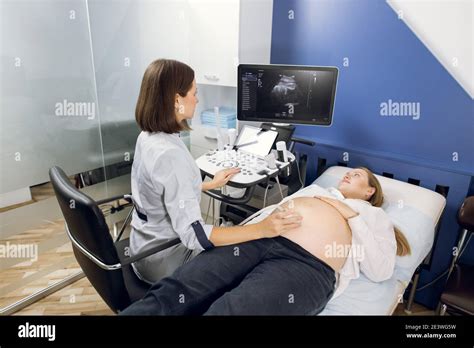 Pregnant Woman Getting Ultrasound Sonogram Scan While Young Concentrated Female Doctor