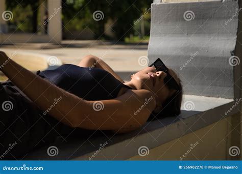 Young Woman Brunette Slender Dressed In Black And Wearing Sunglasses