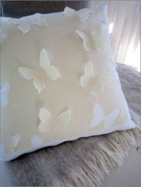 A White Pillow With Butterfly Appliques On It Sitting On Top Of A Bed