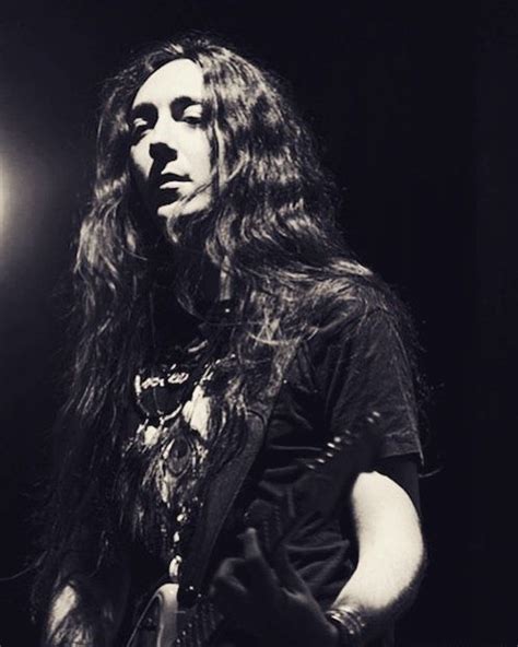 A Man With Long Hair Standing In Front Of A Microphone And Holding An