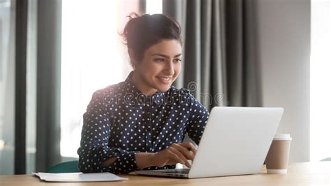 Happy Young Indian Businesswoman Using Computer Sit At Office Desk
