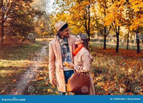 Young Couple In Love Walks In Autumn Forest Among Colorful Trees