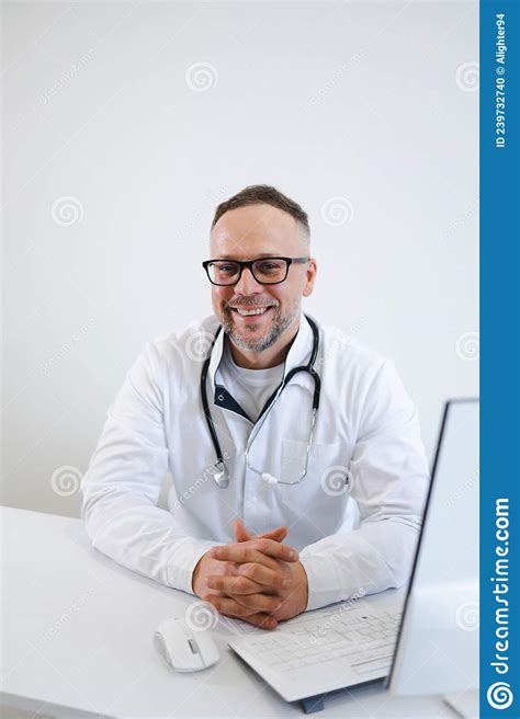 Portrait Of A Happy Male Doctor Sitting At His Desk In The Office