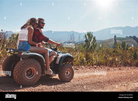 Happy Young Couple In Nature On A Quad Bike Young Man And Woman