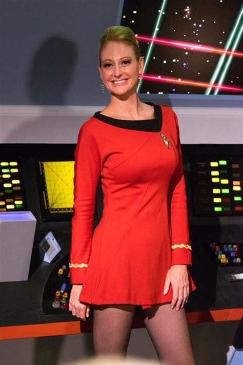 A Woman In A Red Dress Standing Next To A Control Panel With Lights On It