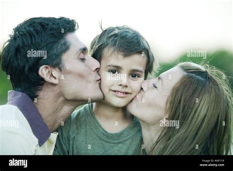Boy Being Kissed On Both Cheeks By Parents Smiling At Camera Stock