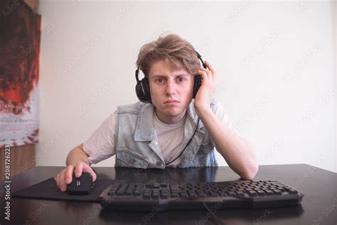 Sad Teenage Gamer Sits At Home Behind A Computer And Plays Video Games