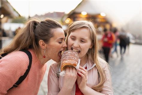 Modern Mother And Child At Fair In City Eating Trdelnik Stock Photo