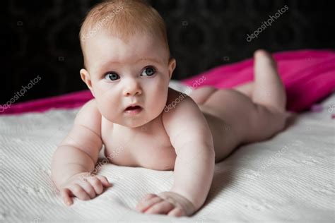 Infant Lying On A White Rug And Surprised Looks Away — Stock Photo