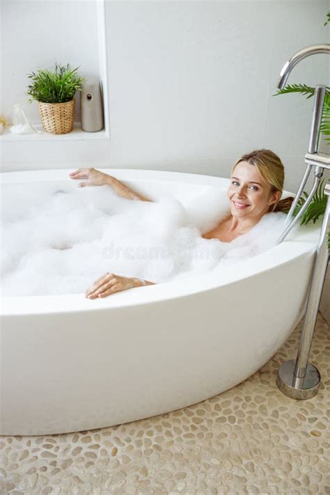 Portrait Of Happy Beautiful Young Blonde Female Lying In Hot Bathtub In Morning And Smiling
