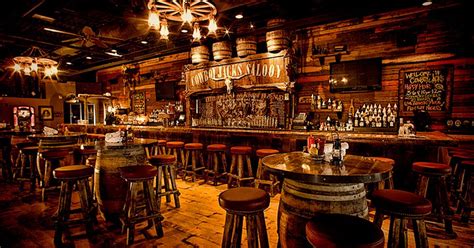 An Old Fashioned Bar With Wooden Stools And Lights Hanging From The