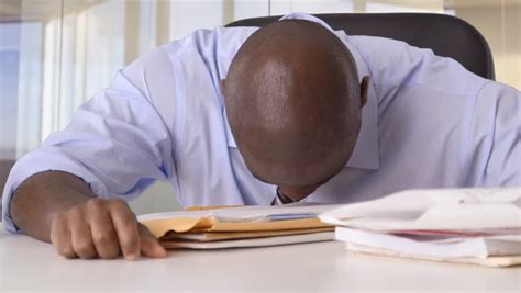 Stressed African American Businessman Banging Head On Desk Stock