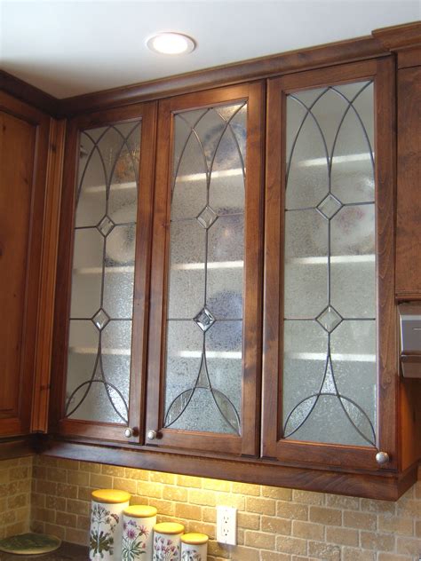 A Kitchen With Wooden Cabinets And Stained Glass Doors On The Back Wall