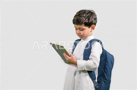 بورتريه لطالب مدرسي عربي خليجي سعودي يرتدي حقيبة ظهر مدرسية، ارتداء الزي المدرسي التقليدي