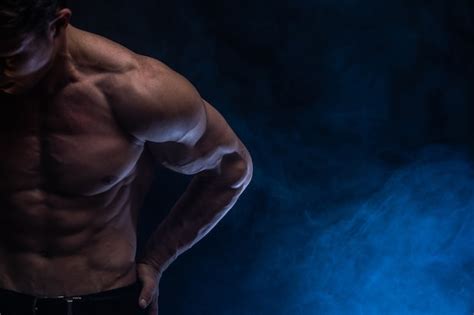 Мускулистый мужчина показывает мышцы изолированные на черном фоне с