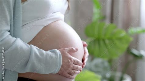4k Pregnant Mother Holding Baby Clothes In Hands Happy Expectant