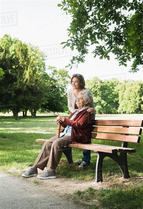 Senior Woman Sitting On Park Bench In Park With Granddaughter Stock Photo Dissolve