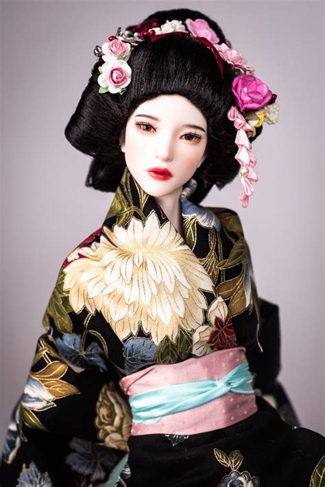 A Doll Wearing A Black And Pink Kimono With Flowers In Her Hair Sitting On A Chair