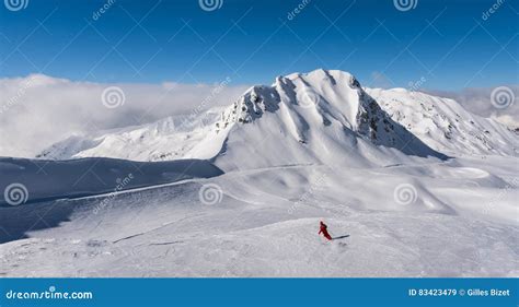 A Skier Alone On The Ski Slopes With Summits And Blue Sky Stock Image