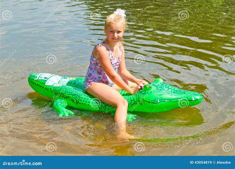 Girl Swimming In The River With Inflatable Crocodile Stock Image