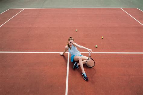 Игрок тенниса сексуальной девушки держа ракетку тенниса на суде