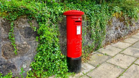 Red Post Office Pillar Box In Front Of Stone Wall Covered In Ivy