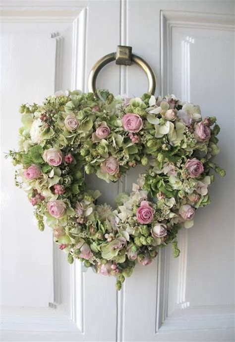 A Heart Shaped Wreath With Pink And White Flowers Hanging On The Front