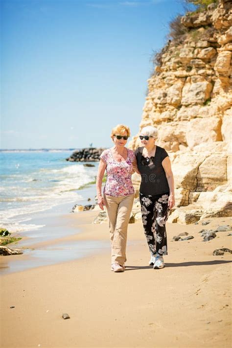 Two Elderly Women Are Walking Along The Rocky Shore Stock Image Image