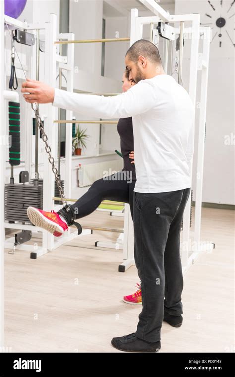 Personal Trainer Instructing Woman How To Use Cable Crossover Machine