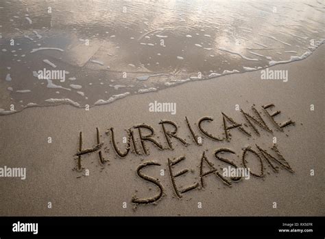 Hurricane Season message handwritten in smooth sand on the shore of a