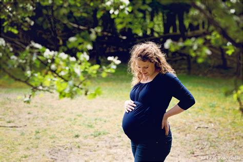 a pregnant woman standing in the grass with her hands on her hips
