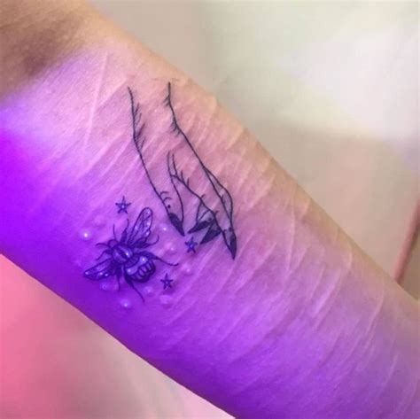 A Small Tattoo On The Arm Of A Woman With Flowers And Stars Around Her