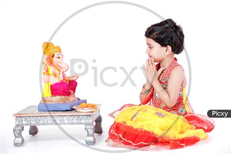 Image Of Indian Girl Child Offering Prayer To Lord Ganesh Statue On An