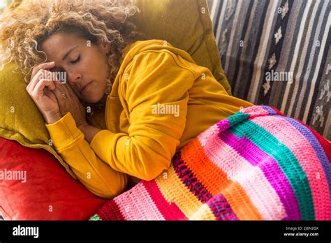 tired woman sleep by day on the sofa with colorful cover stress and sunday time indoor life