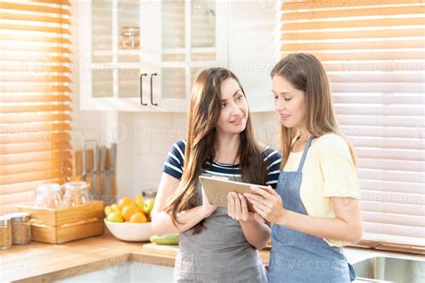 lindo lésbica casal cozinhando saudável comida olhando em digital tábua às moderno cozinha