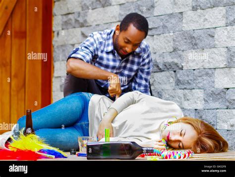 Woman Wearing Casual Clothes Lying Drunk Passed Out On Wooden Surface Man Sitting Beside Her