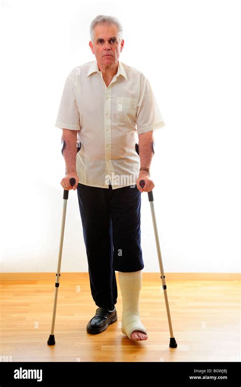 A Man With A Broken Leg On Crutches Against A White Background Stock