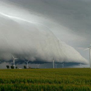 A Large Cloud Looms Over Wind Turbines In A Green Field