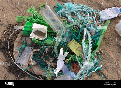Collection Of Assorted Flotsam Shoreline Rubbish On Sandy Beach