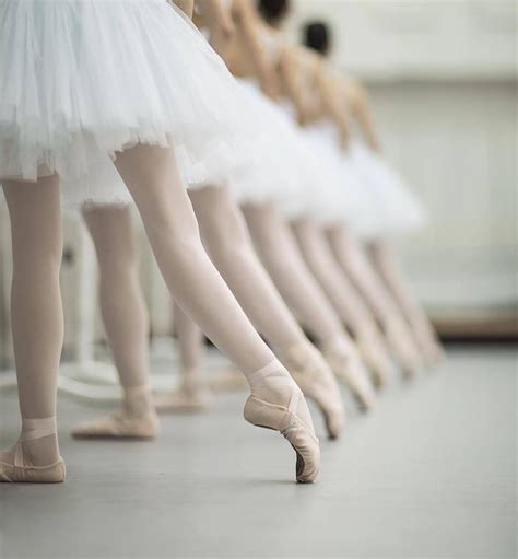 Several Ballerinas Are Lined Up In White Tutu Skirts And Ballet Shoes