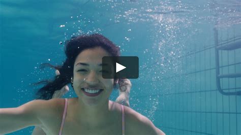 Beautiful Woman Swimming Underwater In Pool Smiling Waving Hand