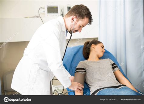 Handsome Male Doctor Measuring Blood Pressure Female Patient Lying