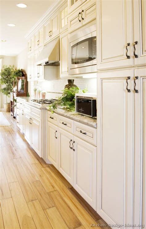 How to keep white kitchen cabinets clean: Antique White Kitchen with Wood Floors and an Island Sink