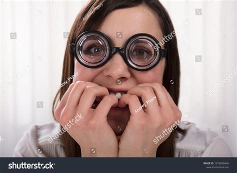 Contemplated Nerd Woman Wearing Eyeglasses Biting Stock Photo
