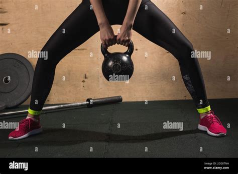 athletic woman exercising with kettle bell while being in squat position muscular woman doing